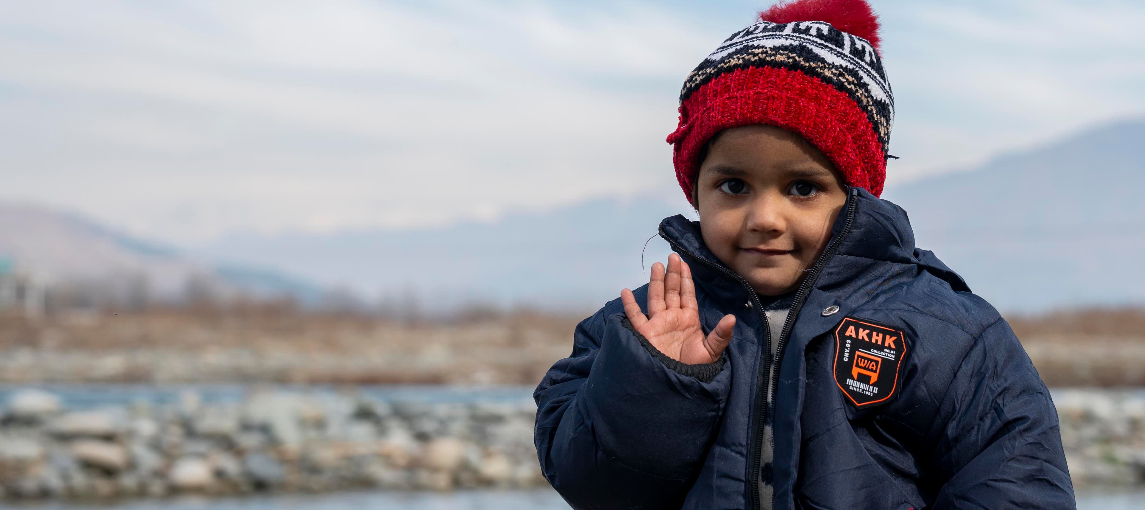 Flicka i vinterkläder som vinkar – Pakistan 2026 - desktop widget