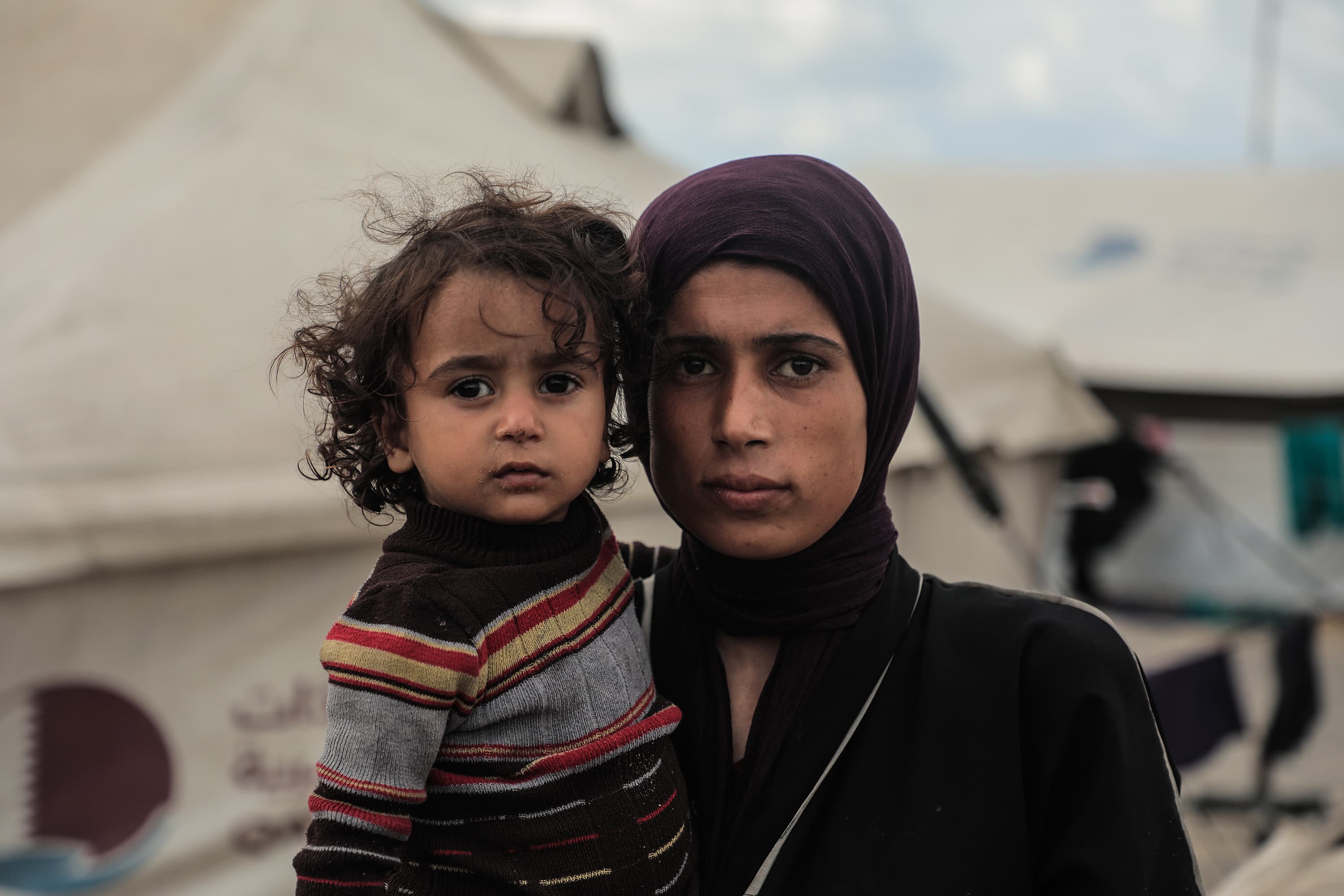 Barn i mammas famn - tittar in i kameran - Gaza 2025