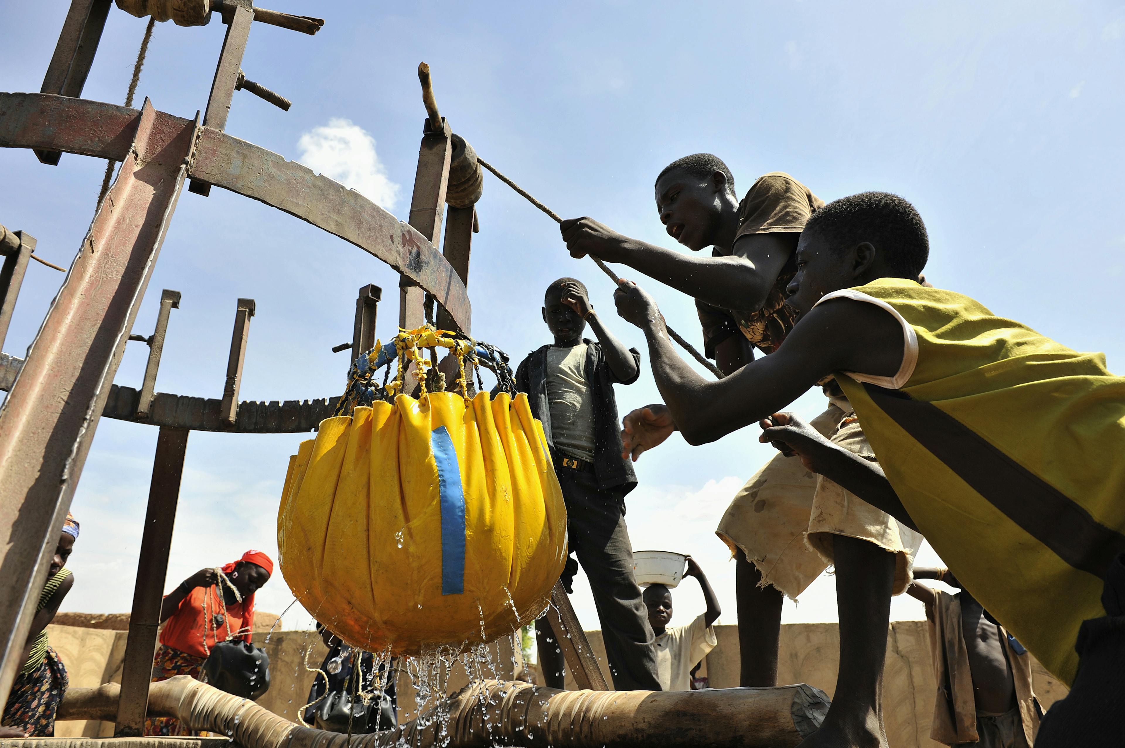 Barn hämtar vatten i en gammal brunn