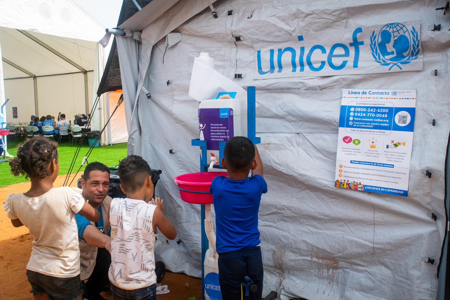 Barn tvättar händerna vid UNICEF-tält - Venezuela 2026
