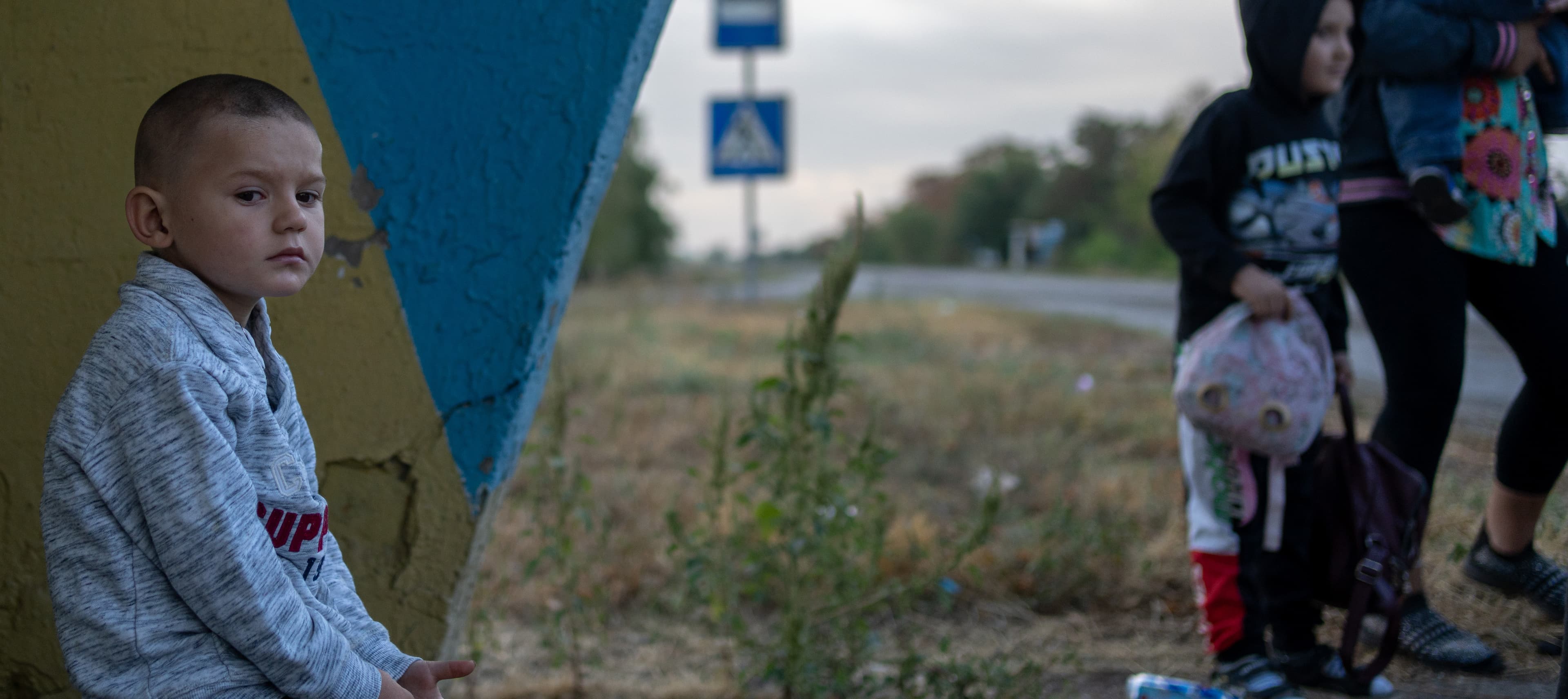 Pojke med familj - busshållplats - Ukraina 2024